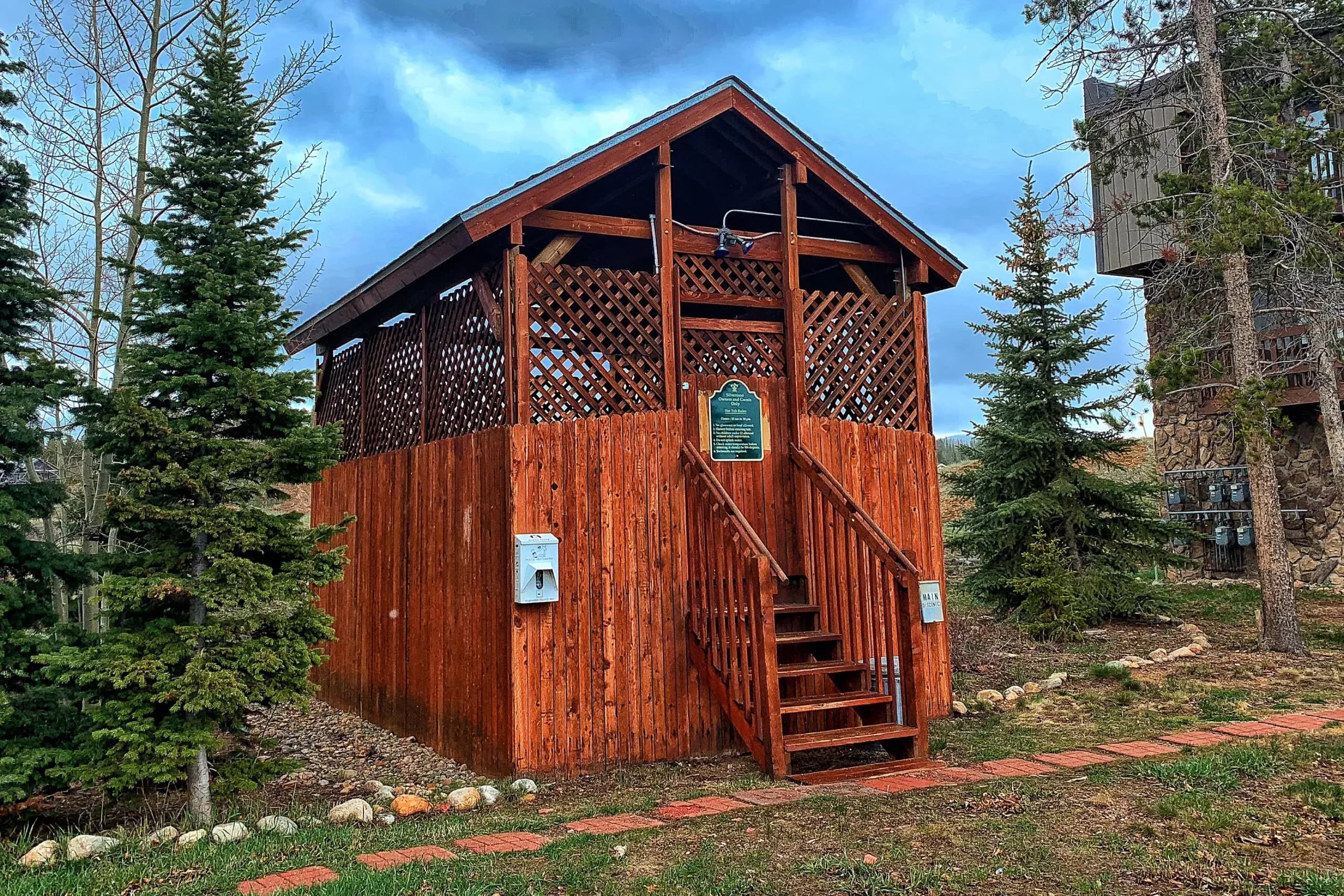 The shared hot tub set in a cedar gazebo under the pines
