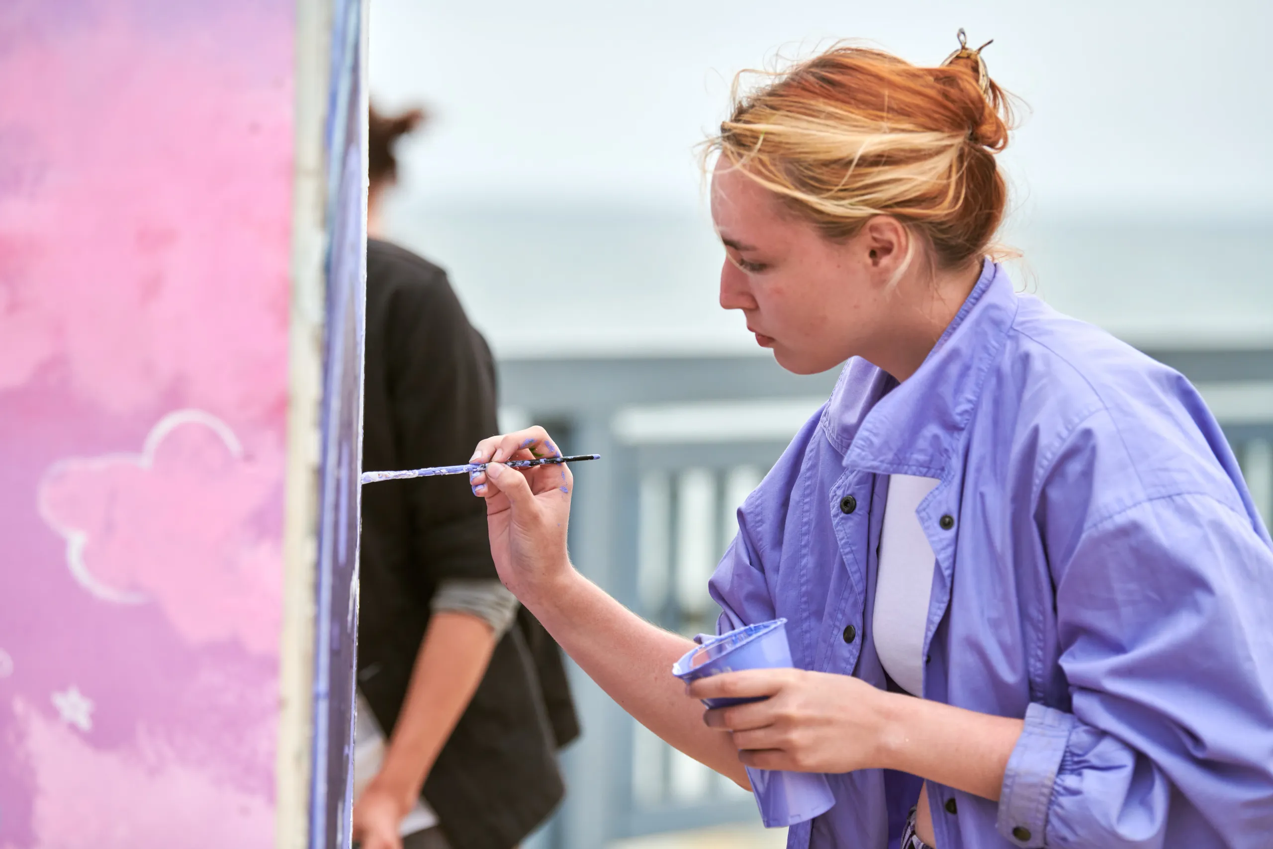 A large outdoor mural being painted on a building